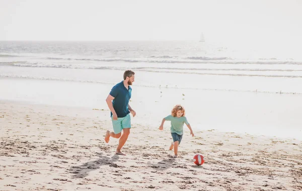 父と息子はビーチでサッカーやサッカーをします。幸せな家庭のコンセプト. — ストック写真