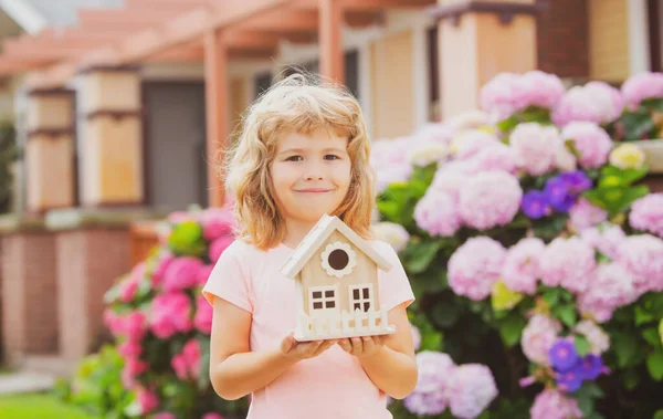 Diseño de la casa de sus sueños. Niño jugando con el modelo de casa pequeña al aire libre en el jardín en casa. — Foto de Stock