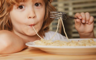 Makarna, spagetti ve yakın plan yiyen sarışın bir çocuğun portresi. Tatlı çocuk suratı. Pozitif duygusal çocuk.