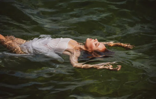 美丽而性感的女人躺在海滩边的水里. — 图库照片