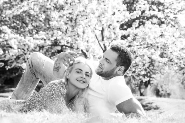 Feliz casal de primavera apaixonado se divertindo. Dois jovens relaxando em flores sakura. Amantes sorridentes relaxando no parque. Família sobre a natureza florescer fundo. Relacionamentos e namoro. — Fotografia de Stock