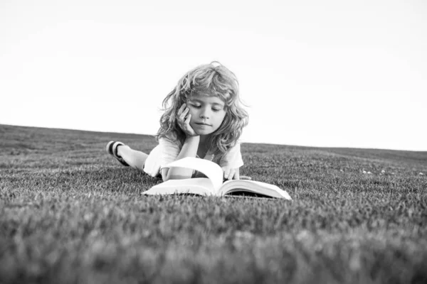 Criança inteligente menino ler livro no parque ao ar livre no dia de verão. Crianças inteligentes. — Fotografia de Stock
