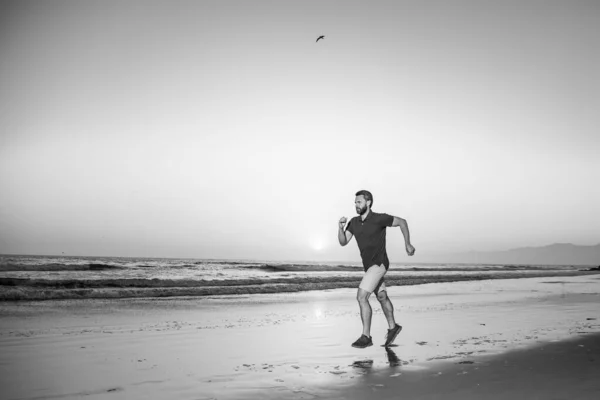 Бегун на пляже бежит на тренировку. Активный здоровый бегун бегает на свежем воздухе. Молодой человек тренируется на пляже утром. — стоковое фото