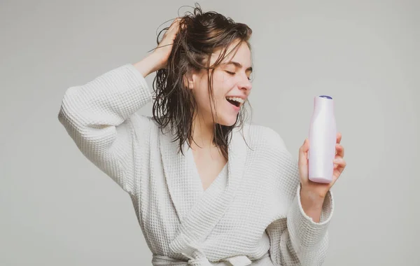 Frau berührt ihr Haar. Frau hält Flaschenshampoo und Conditioner in der Hand. Glückliche junge Frau mit Balsamflasche und Haarmaske. Schönheitsprodukt. — Stockfoto