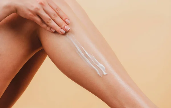 Applying moisturizer cream on legs. Cellulite or anti cellulite treatment. Cosmetic cream on woman leg with clean soft skin.