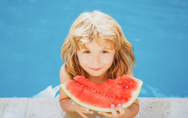 Barn äter vattenmelon nära poolen under sommarlovet. Barn äter frukt utomhus. Hälsosam mat för barn. Liten pojke leker i poolen med en skiva vattenmelon. — Stockfoto