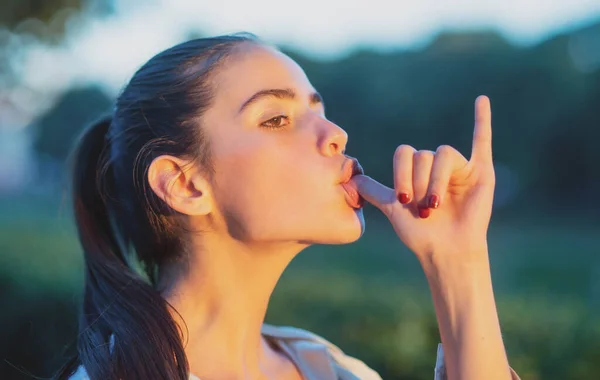 Beautiful girl face closeup, outside portrait of young woman. Beautiful young woman, girl with smoke marijuana sign. Lick finger gesture. Summer romantic casual woman. Girl sucking thumb on. — Foto Stock