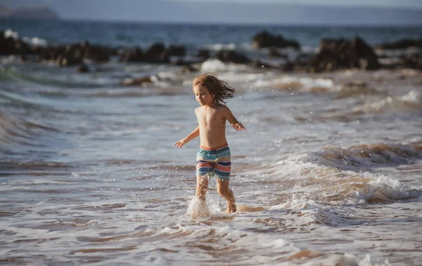 Un chico corriendo en la playa. Niño feliz correr en el mar en las vacaciones de verano. Viajes y aventuras en el mar o en el océano. — Foto de Stock