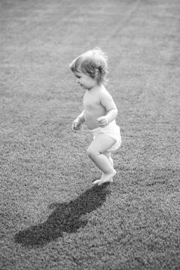 Parkta bahar mevsimi. Güzel ilkbahar yeşil tarlasında bebek. İlk adım.