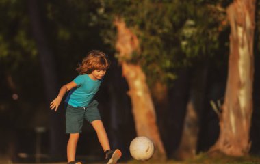 Futbol oynayan bir çocuk, mutlu bir çocuk, spordan hoşlanan bir çocuk, çocuk aktiviteleri, küçük bir futbolcu. Park 'ta çocuk futbolcu.