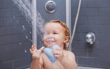 Gülümseyen bir bebek. Kafasında köpük olan mutlu çocuk. Duştaki komik çocuk..