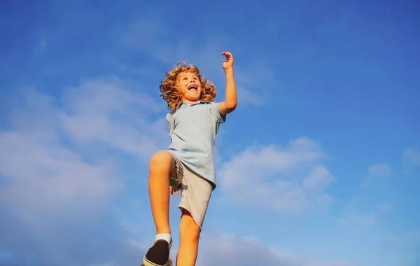 青い空を背景に走って飛び跳ねている男の子。幸せな子供の女の子は日当たりの良いフィールドで遊ぶ、夏の自然アウトドアライフスタイル. — ストック写真