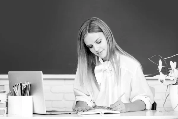 Porträt einer Studentin, die in der Schule oder an der Universität auf einem Notizbuch schreibt. — Stockfoto