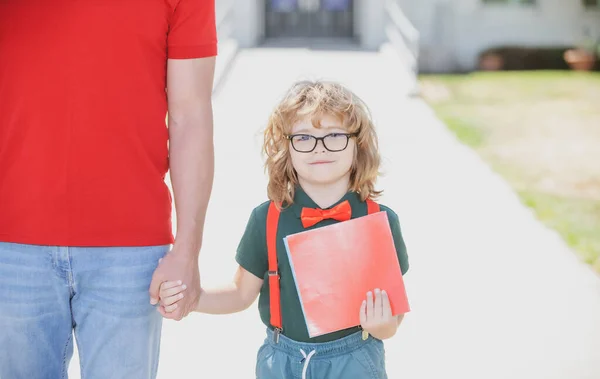 Ragazzino nerd. Scuola, famiglia, educazione e concetto di outdoor. Genitore che tiene per mano il figlio con lo zaino all'aperto, torna a scuola. — Foto Stock