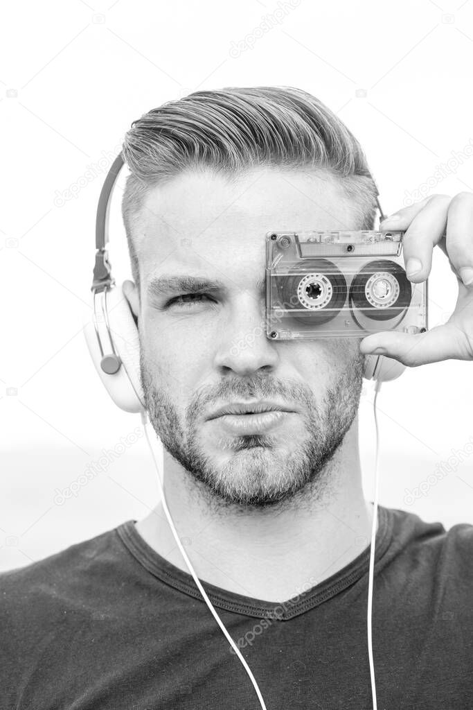 Man listening music with cassette and headphones. Emotional portrait guy. Retro player. Young bearded man in the style of the 90s.