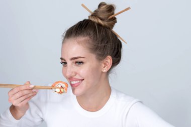 Suşi yiyen seksi bir kadının portresi. Suşi rulo, sashimi. Manken kız yemek çubuklarıyla suşi yiyor. Yemek çubuklarıyla saç kesimi, sağlıklı Japon yemekleri yemek..