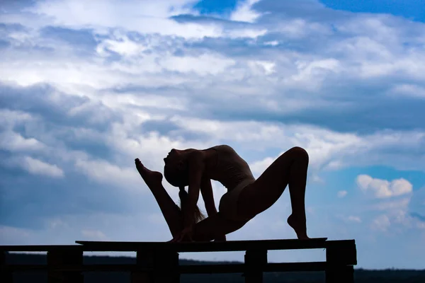 Fitness mulher esporte esticando-se antes do treinamento. Silhueta de modelo de ajuste feminino. Alongamento e motivação. Fundo céu nublado. — Fotografia de Stock