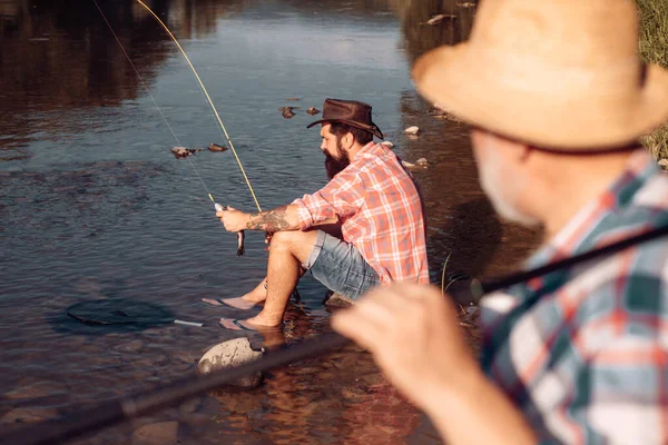 Hombre mayor maduro con amigo pescando. Vacaciones de verano. Gente feliz y alegre. Hombres barbudos capturando peces. Pescador con caña de pescar. Actividad y hobby. —  Fotos de Stock