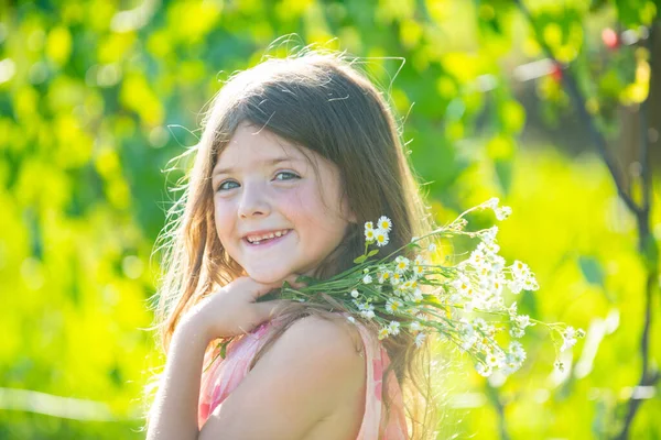 Portret dziewczynki na łące. Mały słodki dzieciak z kwiatami w ogrodzie. Dzieci bawią się na zewnątrz. Dzieciak gra na świeżym powietrzu. Koncepcja szczęśliwego dzieciństwa i letniego wypoczynku. — Zdjęcie stockowe