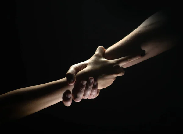 Two trength ands. Helping hand to a friend. Rescue or helping gesture of hands. Concept of salvation. Hands of two power people at the time of rescue, help. Isolated on black background. — стоковое фото