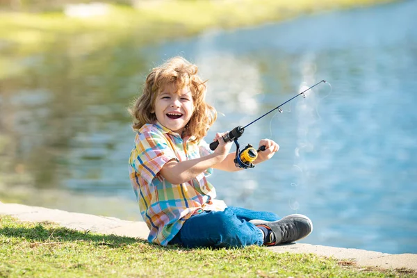 Funny happy little kid fishing on weekend. A fisherman boy stands in the lake with a fishing rod and catches fish. Stock Picture