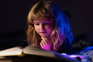 Mutlu çocukluk, rüya gören çocuk. Çocuk uyumadan önce yatakta kitap okuyor. Evdeki küçük çocuk yatakta uzanıp kitap okuyor..