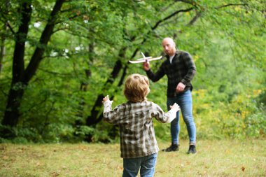 Babasıyla oyuncak uçakla oynayan tatlı bir çocuk. Babalar Günü. Baba ve oğlu dışarıda oyuncak uçak oynuyorlar..
