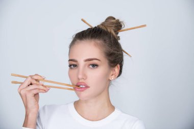 Yemek çubuklarıyla dudak karıştıran seksi, şehvetli bir kadın. Sushi reklamı için seksi bir ağız. Stüdyo izole edilmiş portre.