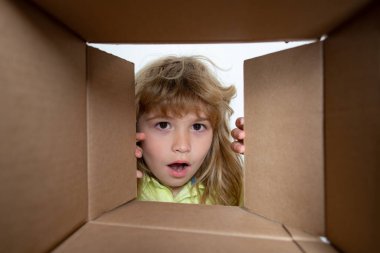 Çocuk paketleri açıyor ve karton kutuyu açıyor. Sürpriz bir suratla içeri bakıyor. Çocuk açma paketi.