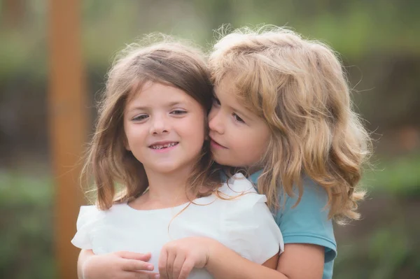 Δύο μικρά παιδιά αγκαλιάζονται και φιλιούνται στον καλοκαιρινό κήπο. Τα παιδιά είναι ερωτευμένα. Φιλία και παιδική ηλικία. — Φωτογραφία Αρχείου