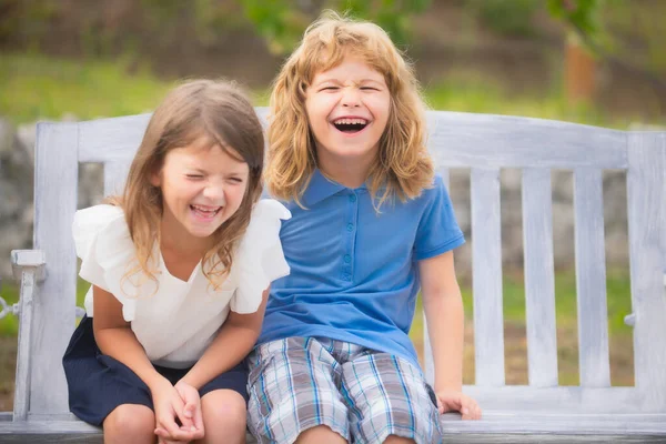 Двое улыбающихся смеющихся детей отдыхают на открытом воздухе в летнем парке. Брат и сестра счастливо ходят на природе. Братья и сестры мальчик и девочка играют в саду. — стоковое фото
