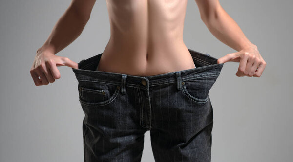 Успешная потеря веса, женщина с слишком большими джинсами после диеты. Большие брюки в концепции потери веса.