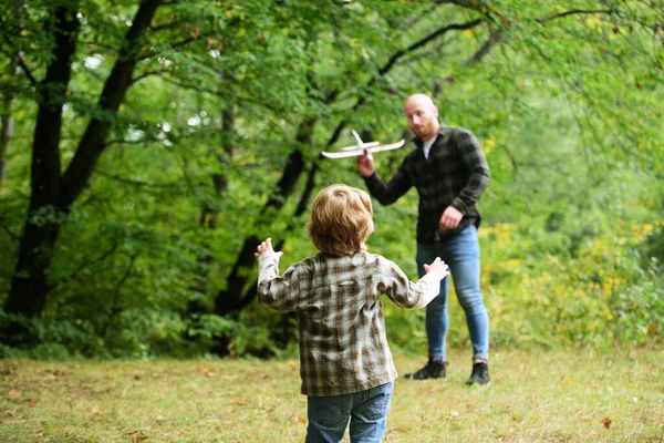 Babasıyla oyuncak uçakla oynayan tatlı bir çocuk. Babalar Günü. Baba ve oğlu dışarıda oyuncak uçak oynuyorlar..