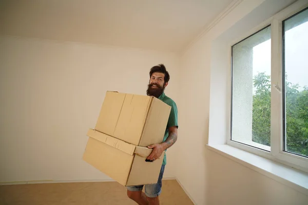 L'homme drôle porte ses affaires dans des boîtes. Je déménage dans un nouvel appartement. Jeune homme heureux avec des boîtes en carton. Homme portant des boîtes empilées le jour du déménagement. — Photo