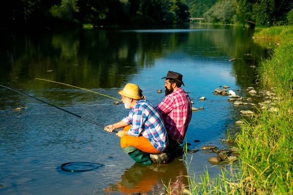 Father and mature son fisherman fishing with a fishing rod on river. — Stock Photo, Image