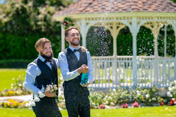 Gay paar bruiloft met champagne splash. gay paar open mousserende wijn. — Stockfoto