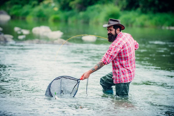 Pescador pescando en un río. Hombre pescador relajado con una caña de pescar en un día de verano. — Foto de Stock