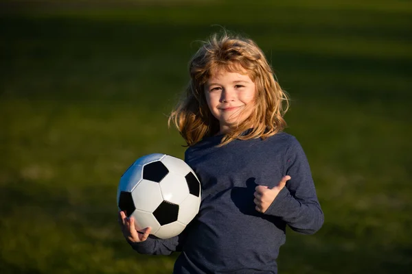 Chłopiec gra w futbol na boisku. Dzieciak grający w piłkę podnosi rękę na znak sukcesu. Szkolenia dla dzieci sportowych. — Zdjęcie stockowe