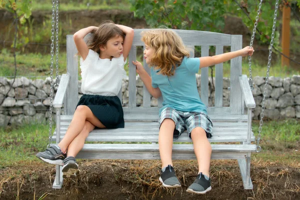 Zwei Kinder im Freien. Portrait von bezaubernden Bruder und Schwester lächeln und lachen zusammen, während sie auf Schaukel im Freien sitzen. Glückliche Kinder schaukeln in Gartenschaukel. — Stockfoto