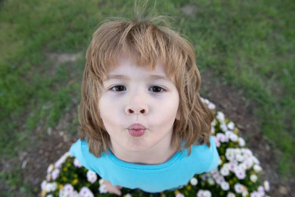 Charmigt blont barn på bakgrunden av blommor på sommaren. Söt liten barn som arbetar i trädgården, barn som tar hand om blommor, njuter av varm och solig dag. — Stockfoto