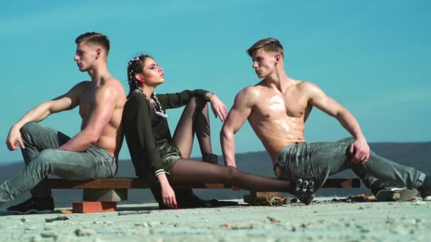 Group of fashion youth. Two bare torso muscle men and charisma charm glamor girl posing outdoor. Group of teens, boys girls in stylish clothes. Youth culture, style and fashion. Fashionable portrait. — ストック動画