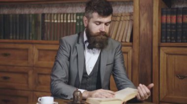 Erkekler kitaplığın arka planında kitap okuyor. Edebiyat kütüphanesi. Okuyucu içeride oturur ve kitap okur. Klasik takım elbiseli sakallı adam okumayı sever. Kütüphanedeki kendinden emin yetişkin öğrenci..