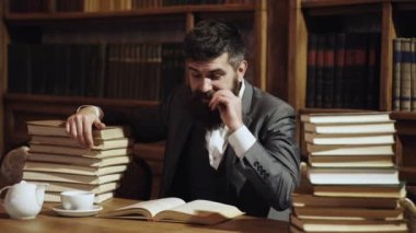 Kütüphanede sakallı adam ve arka plan kitapları. Orta yaşlı bir adam kütüphanede kitap okuyor. Profesör..