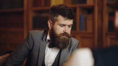 Klasik takım elbiseli iş adamı kitap okudu. Eski moda iş adamları. Kütüphanede arka planda kitapları olan işadamları.