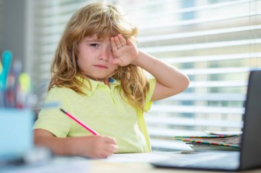 Ödev yaparken yorgun ve üzgün bir okul çocuğu. Çocuk bir kalem tut ve evde çiz. Genç öğrenci masada otururken çizim yapıyor..