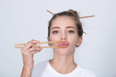 Ağzında çubuklar olan komik genç bir kadın. Çubuklu seksi dudaklar..