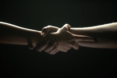 Eller siyah arka planda hareket ediyor. Yardım eli uzatıyorum. Destek ve yardım, kurtuluş. Kurtarma sırasında iki kişinin güçlü ve güçlü görüntüsü. Kurtuluşa uzanan ellere yardım ediyorum. Sıkı tutun..
