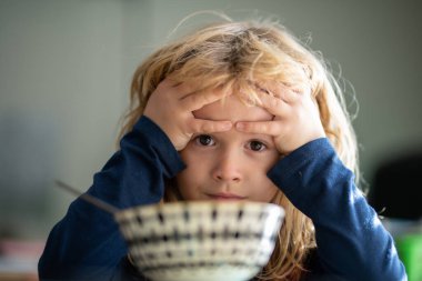 Çocuk kahvaltı yapsın. Üzgün çocuk öğle yemeğinde sağlıklı tavuk çorbası içiyor. Mutsuz bir çocuk evde yemek yiyor, kreşte ya da anaokulunda. Çocuk bakımı ve çocukluk.