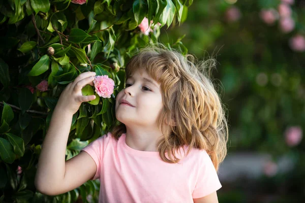 Cara de criança primavera. Close up retrato de uma pequena criança loira com flor de primavera. Miúdos engraçados no quintal. As crianças fecham o rosto no fundo da flor. Crianças menina jogar em flores de primavera. — Fotografia de Stock