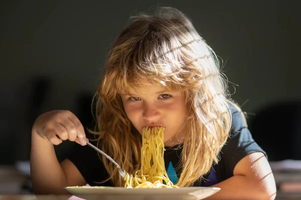 Bulanık arka planda yemek yiyen çocuk. Aç küçük çocuk yemek yiyor. Çocuklar için ev yemeği. Lezzetli yemekler, dağınık çocuk spagetti yiyor. — Stok fotoğraf